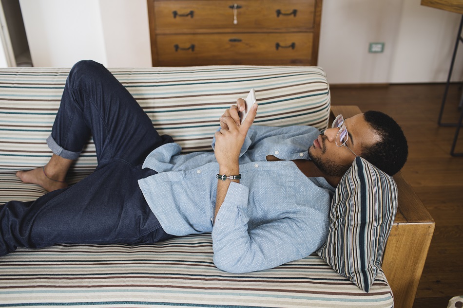 Young Man Relaxing With His Phone On The Couch
