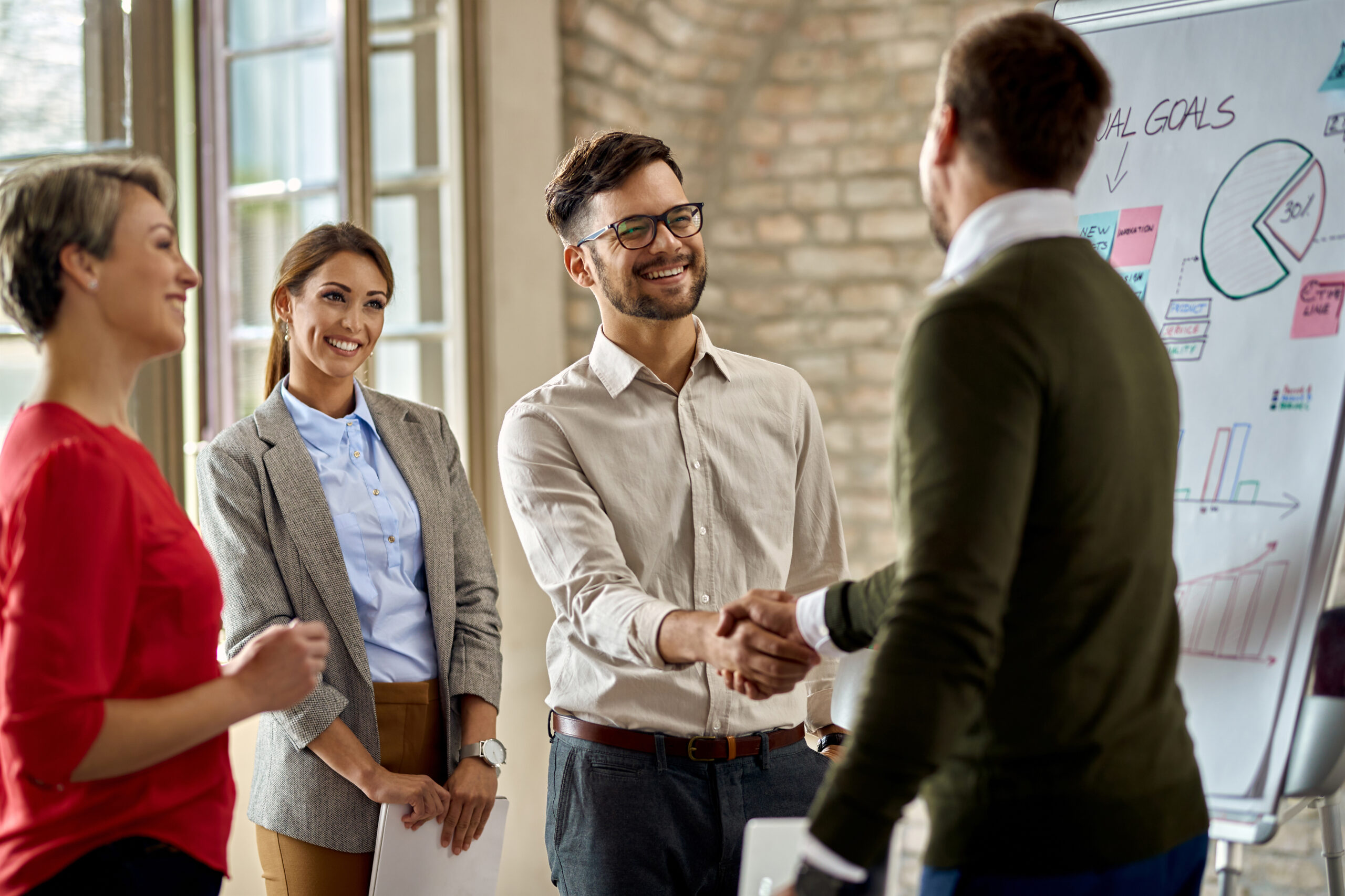 Happy coworkes shaking hands after business presentation in the office.